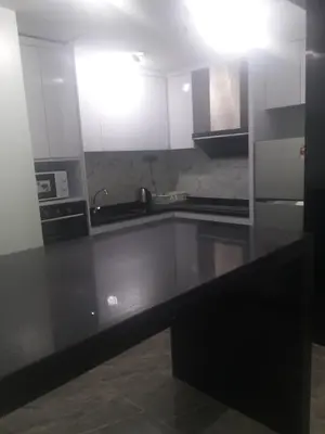 a kitchen with white cabinets and a black counter top at Happy holiday suites at times square KL in Kuala Lumpur