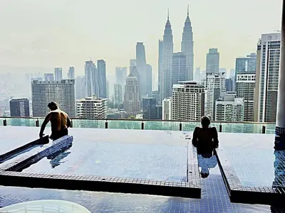two people walking on the roof of a skyscraper at Lucky Suites KLCC By LUXE Infinitum in Kuala Lumpur