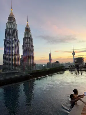 two people swimming in a river with tall buildings at KL Star Residences By Nexus Nest 25 in Kuala Lumpur