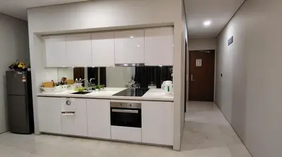 a kitchen with white cabinets and a sink and a refrigerator at Sky Suites KLCC By Stay Happy in Kuala Lumpur