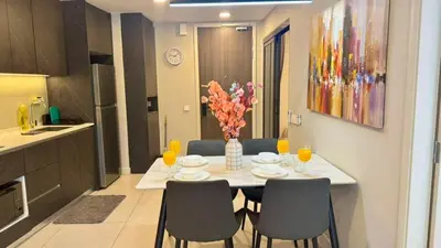 a dining room table with chairs and a vase of flowers at Warm & Cozy 2Bedroom Apartment at The Atrium Ampang by OKBnB in Kuala Lumpur