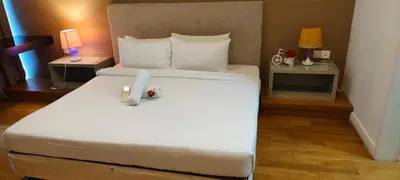 a bedroom with a large white bed with two tables at platinum suites klcc By Palmas in Kuala Lumpur