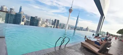 a large pool with people sitting in chairs next to a city at platinum suites klcc By Palmas in Kuala Lumpur