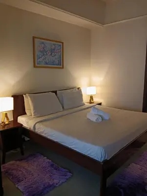 a bedroom with a bed with two lamps and two rugs at Crown Suits At Times Square in Kuala Lumpur