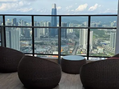 a balcony with chairs and a table and a city at Trion KL TRX KLCC 6 Pax in Kuala Lumpur