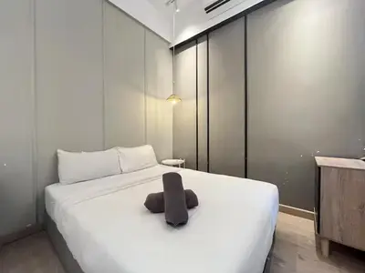 a large white bed with a brown pillow on it at The Colony By Infinitum Q in Kuala Lumpur