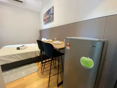a room with a bed and a refrigerator next to a table at The Colony By Infinitum T in Kuala Lumpur
