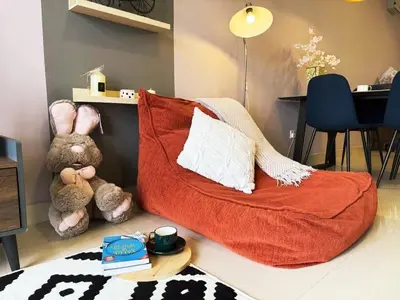 a teddy bear sitting next to a red couch in a room at Trion Skyview Residence KL City Centre in Kuala Lumpur