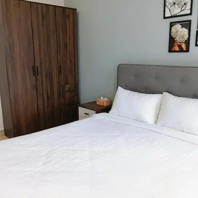 a bedroom with a white bed and a wooden cabinet at Trion Skyview Residence KL City Centre in Kuala Lumpur