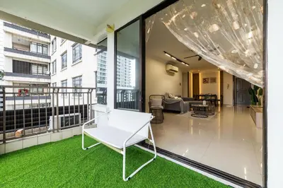 a living room with a white chair on a balcony at Royal Domain KL near Mont Kiara by Sleepy Bear in Kuala Lumpur