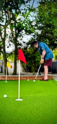 a man playing golf on a putting green with a red flag at Gasing WheelHouse in Petaling Jaya