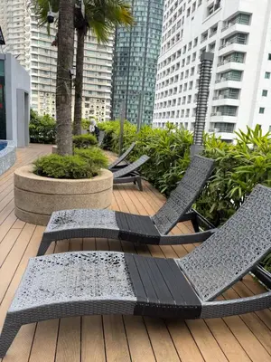 a deck with chairs and palm trees and buildings at Vortex suites klcc by 2 bed 3 bed family suites vibes in Kuala Lumpur
