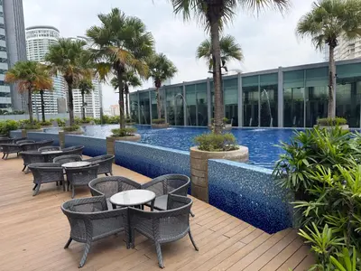 a hotel patio with tables and chairs and a swimming pool at Vortex suites klcc by 2 bed 3 bed family suites vibes in Kuala Lumpur