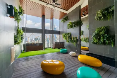 a living room with yellow ottomans and plants at Delightful Studio Suite in Kuala Lumpur