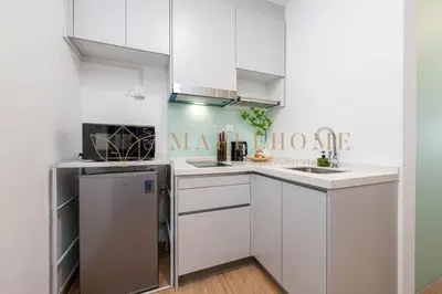 a kitchen with white cabinets and a refrigerator at Delightful Studio Suite in Kuala Lumpur