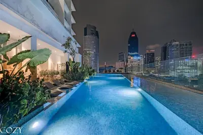 a swimming pool with a city skyline at night at Quill Residence by Infinity pool in Kuala Lumpur