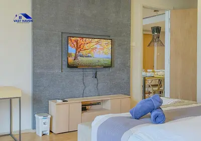 a bedroom with two beds and a tv on a wall at 188 Suites KLCC by VastHaven in Kuala Lumpur