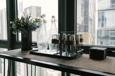 a table with two bottles and flowers on a window at Chic Cityscape Homestay in Bukit Bintang 1-5 people in Kuala Lumpur