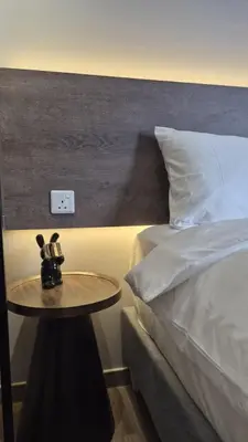 a night stand next to a bed with a table next to it at Agile Bukit Bintang TRX 4min MRT Studio Good View Netflix #031 in Kuala Lumpur