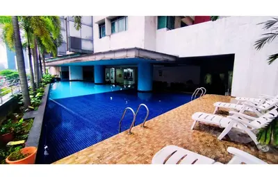 a swimming pool with white chairs and a building at Taragon Elite Residence in Kuala Lumpur