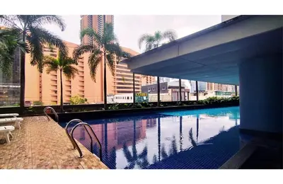 a swimming pool with palm trees and a building at Taragon Elite Residence in Kuala Lumpur