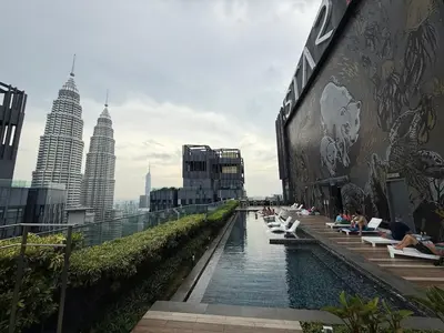 a pool on the side of a building with people sitting at Star Residence KLCC By Nexus 72 in Kuala Lumpur