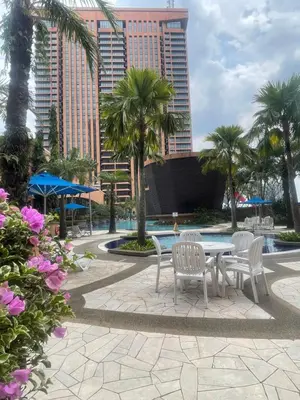 a patio with a table and chairs and palm trees at Sunrise Residence At Berjaya Times Square AR in Kuala Lumpur