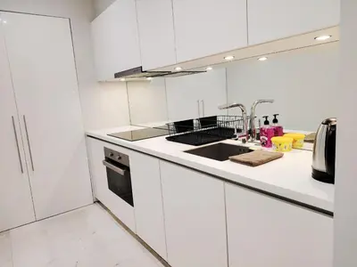 a white kitchen with white cabinets and a sink at KLCC Luxe High speed wifi 2BR Residence in Kuala Lumpur