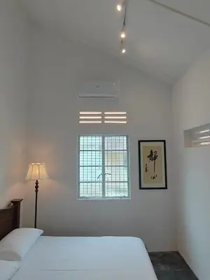 a white bedroom with two beds and a window at Zen Retreat KL in Kuala Lumpur