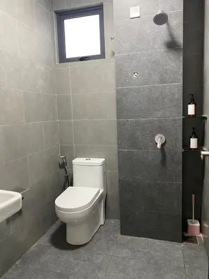 a bathroom with a toilet and a sink and a window at Neu Suite by Triple A in Kuala Lumpur