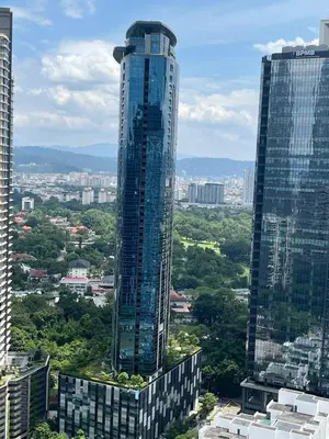 a tall glass building in a city with trees at Eaton Hotel \u4f0a\u987f\u9152\u5e97 \u4e94\u661f\u7ea7\u9152\u5e97 in Kuala Lumpur