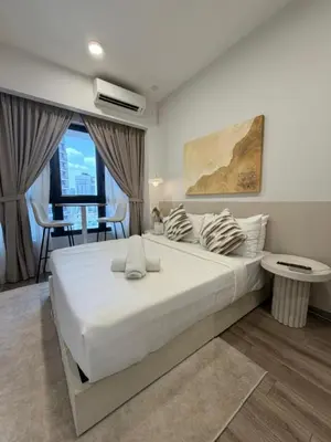 a bedroom with a large white bed and a table at Agile Landmark Suites by Kuala Lampur City in Kuala Lumpur