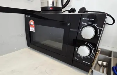 a black microwave sitting on top of a counter at Chillax Studio Near KLCC Gleneagles in Kuala Lumpur