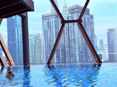 a woman in a infinity pool with a view of the city at Scarletz Luxury Suites KL in Kuala Lumpur