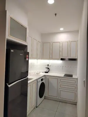a kitchen with white cabinets and a black refrigerator at skyscraper by cozy in Kuala Lumpur