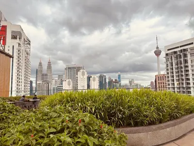 two people sitting on a bench in front of a city at Majestic Residence KLCC By Homestay in Kuala Lumpur