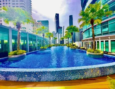 a large swimming pool with palm trees in a city at Vortex suites klcc 8pax with City views in Kuala Lumpur