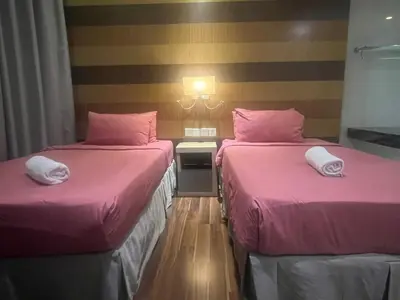two beds in a hotel room with pink sheets at D Majestic hosted by Super Tang in Kuala Lumpur
