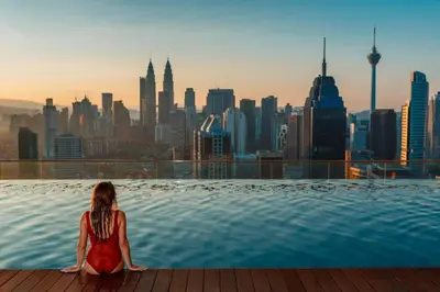 a woman sitting in a infinity pool overlooking a city at The regalia KLCC panorama view in Kuala Lumpur