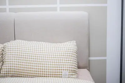 a bed with a checkered pillow on top of it at Cozy Home to explore KL City KLCC TRX Bkt Bintang in Kuala Lumpur