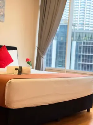 a bed with a red pillow and a window at Sky Suites KLCC by TD Luxury Homestay in Kuala Lumpur