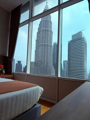 a bedroom with a view of a tall building through a window at Sky Suites KLCC by TD Luxury Homestay in Kuala Lumpur