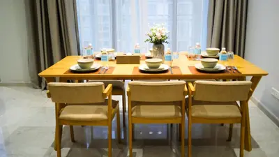 a wooden dining room table with chairs and a vase of flowers at Manor Residences KLCC in Kuala Lumpur