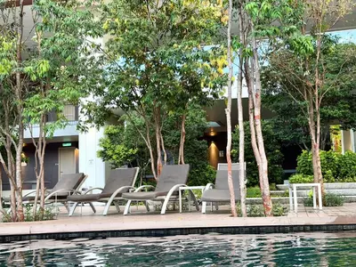 a group of chairs sitting next to a swimming pool at Lucentia Residence Bukit Bintang LalaportBBCC By VELLORA in Kuala Lumpur