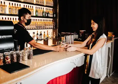 a man and a woman standing at a bar at Scarletz Suites KLCC Rooftop Infinity Pool Near Twin Towers in Kuala Lumpur