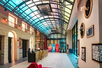 a lobby with a glass ceiling with people sitting at tables at Scarletz Suites KLCC Rooftop Infinity Pool Near Twin Towers in Kuala Lumpur
