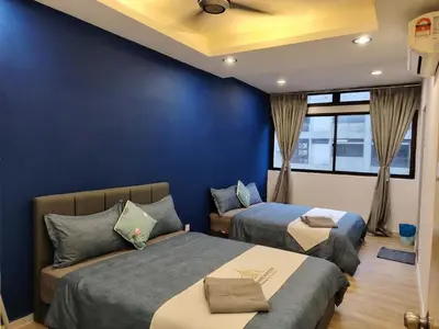 a bedroom with two beds and a blue wall at Fahrenheit88 Suites Bukit Bintang A 2R in Kuala Lumpur