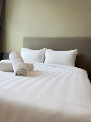 a white bed with two rolled towels on it at PLATINUM SUITES KLCC By CHENLUN in Kuala Lumpur