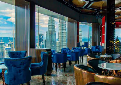 a restaurant with blue chairs and tables and a view of a city at Platinum Suites in Kualalumpur City Center in Kuala Lumpur