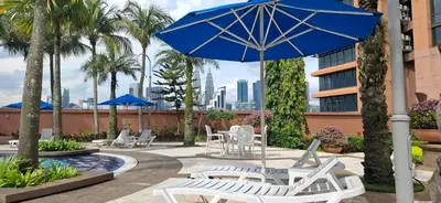 a patio with white chairs and a blue umbrella at BT Apartment times square kl in Kuala Lumpur